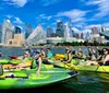 A group of kayakers enjoys a sunny day on the water with a backdrop of modern skyscrapers