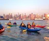 A group of kayakers enjoys a sunny day on the water with a backdrop of modern skyscrapers