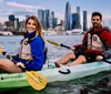 A group of kayakers enjoys a sunny day on the water with a backdrop of modern skyscrapers