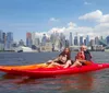 A group of kayakers enjoys a sunny day on the water with a backdrop of modern skyscrapers