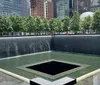 This image shows a memorial reflecting pool surrounded by trees and skyscrapers in an urban setting at twilight