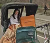 The image shows four smiling adults seated in two pedal-powered rickshaws enjoying a sunny day outdoors