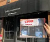 A person is holding an image of the iconic facade of the CBGB music club in front of the current John Varvatos store which now occupies the same location