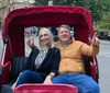 Two people are smiling and making peace signs while sitting in a red pedicab on a city street likely enjoying a leisurely tour