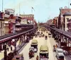 The image depicts a bustling early 20th-century street scene with an elevated train track horse-drawn carriages and vintage automobiles showcasing a vivid snapshot of urban life during that era