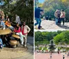 A person is taking a photo of three individuals posing together on a sunny day in what appears to be a park with trees and other people in the background