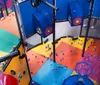 The image shows an indoor playground with colorful floors and scattered soft balls featuring play structures for childrens entertainment