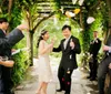 A joyful couple walks through an archway as guests throw flower petals to celebrate their wedding