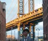 A happy couple in formal attire stands in front of the Brooklyn Bridge with the New York City skyline in the background