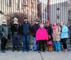 A group of smiling people pose for a photo at an outdoor evening gathering wearing winter clothing