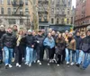 A group of people are posing for a photo on a city street smiling and dressed in warm clothing