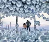 Two individuals stand amidst a cluster of reflective spheres gazing out at an urban skyline from a high vantage point