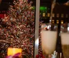 The image shows a bustling crowd of people gathered around a large decorated Christmas tree in an urban setting indicative of a holiday celebration in a city