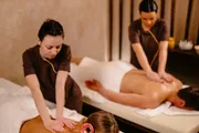 Two massage therapists are providing a relaxing treatment to clients in a serene spa setting.