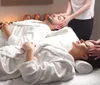 Two massage therapists are providing a relaxing treatment to clients in a serene spa setting