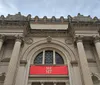 The image shows the neoclassical facade of The Metropolitan Museum of Art in New York highlighted by its iconic THE MET banner