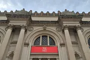 The image shows the neoclassical facade of The Metropolitan Museum of Art in New York, highlighted by its iconic 