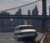 A ferry named Seaport Princess is docked near a pier with the Manhattan Bridge and the New York City skyline in the background