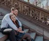 A couple is sharing an intimate moment of closeness while sitting on stone steps giving the impression of happiness and affection