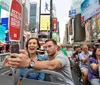 A couple is excitedly taking a selfie on a sightseeing bus in the bustling atmosphere of Times Square