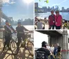 A group of smiling people wearing helmets are standing with bicycles on a sunny boardwalk by the water with a bridge in the background