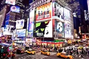 The image shows a vibrant and bustling Times Square at night, illuminated by bright billboards and alive with the iconic yellow cabs of New York City.