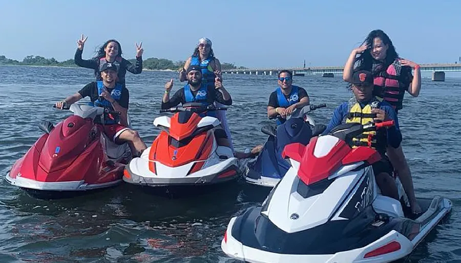 A group of people are posing and smiling on personal watercraft in a large body of water, enjoying a sunny day.