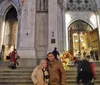 A couple is posing for a photo in front of the entrance to a cathedral adorned with Christmas decorations