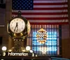 A group of people appears engaged in conversation near the entrance of Grand Central Terminal on a cloudy day with street signs for East 42nd Street and Park Avenue visible above them