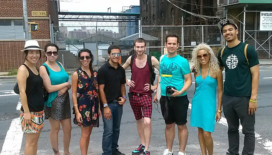 A group of young adults are casually posing for a photo on a city street, creating a lighthearted and diverse urban scene.