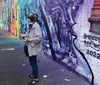 A group of smiling people is standing in front of a colorful graffiti-covered wall