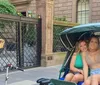 A joyful group of people are taking pedicab rides in what appears to be a city park setting smiling and posing for a group selfie