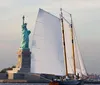 A sailboat passes by the Statue of Liberty on a clear day