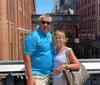 A man and a woman pose for a photo with urban brick buildings and an elevated walkway in the background