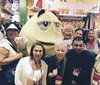 A group of smiling people are posing with a giant MM character at what appears to be a themed store or event