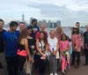 A diverse group of individuals is posing for a group photo with the New York City skyline in the background