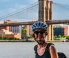 Two cyclists are smiling for the camera on a tree-lined urban street