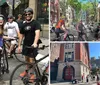 Two cyclists are smiling for the camera on a tree-lined urban street