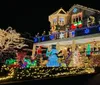 A bustling holiday scene where a crowd gathers in front of festively decorated homes illuminated by Christmas lights and flanked by giant nutcracker statues