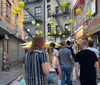 Pedestrians walk down a vibrant street adorned with yellow and green lanterns showcasing the cultural atmosphere of a busy Chinatown district