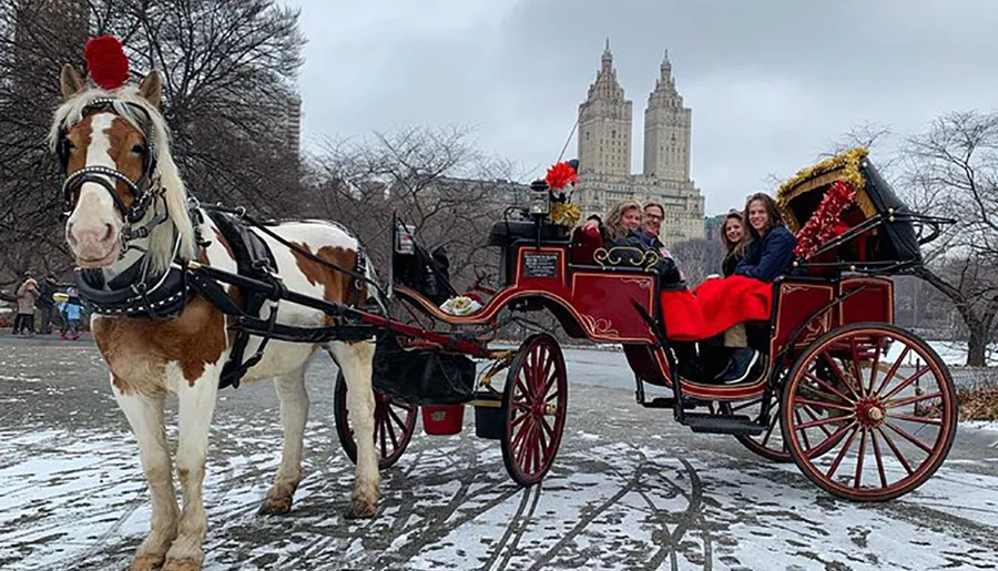 A horse-drawn carriage carries cheerful passengers through a snowy park with an iconic building in the background.