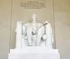 The image shows a large seated marble sculpture of a historic figure inside a neoclassical monument accompanied by an inscription above that pays homage to the individuals legacy