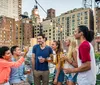 A group of people are enjoying a rooftop gathering during sunset with a view of a city skyline