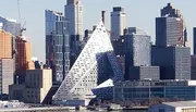 The image displays a modern city skyline with a distinctive triangular-shaped building front and center, accentuating the architectural diversity among the urban landscape.