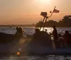 A group of people in a rigid-hulled inflatable boat speed across the water at sunset with the American flag flying at the stern