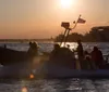 A group of people are speeding on a rigid inflatable boat across the water at sunset with the American flag displayed at the stern