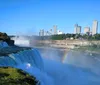 This is an image showing the majestic Niagara Falls with a vibrant rainbow arching over the mist and a city skyline in the background