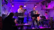 A jazz band performs on stage in an intimate venue with a cozy ambiance.