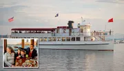 The image shows a multi-level passenger boat sailing on calm water, with people visible on the open upper deck, flanked by the American flag and two other flags, and a smaller inset image at the bottom left corner portrays a family pointing out towards a view, presumably seen from the boat.