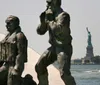 The image features bronze statues of military figures foregrounded against the backdrop of the Statue of Liberty in the distance
